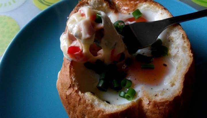 Jajko zapiekane w bułce z serem, papryką i szczypiorkiem.
